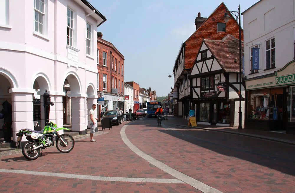 A pink-painted rendered front beside a timber-framed building in Godalming town centre