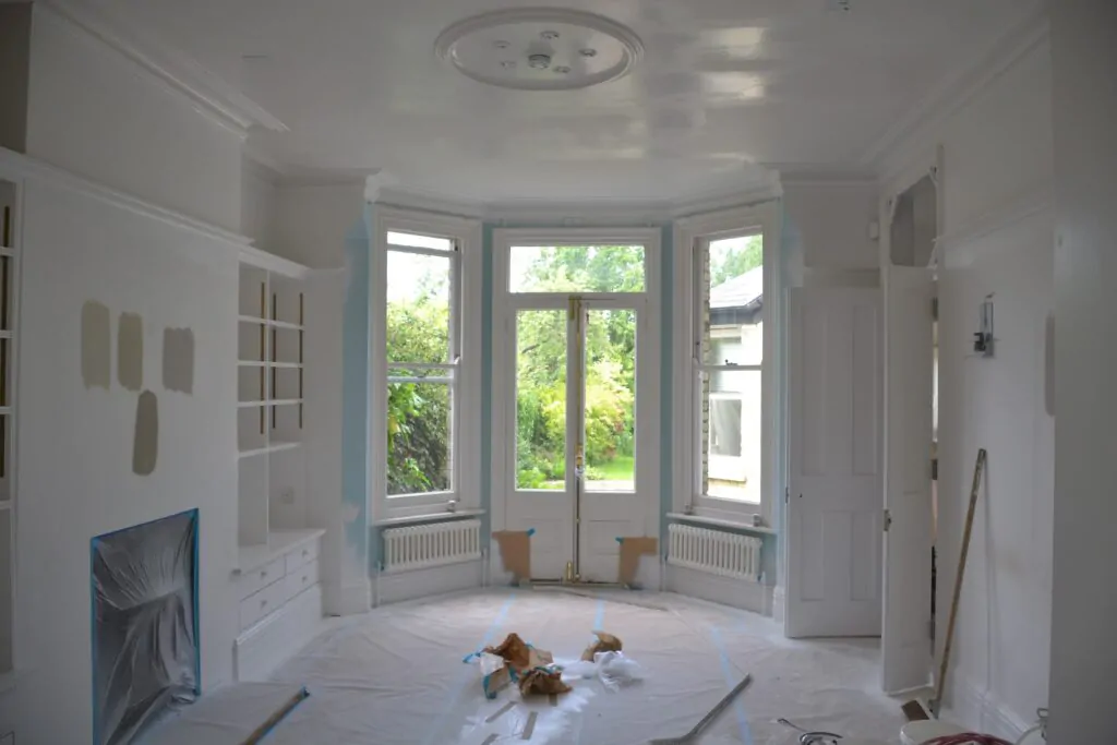 Room under renovation with large bay windows and freshly painted walls and ceiling