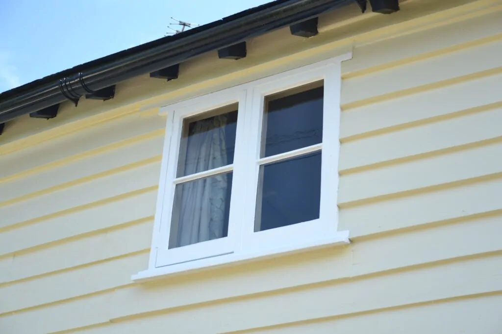 White-framed windows on a repainted timber-clad house exterior