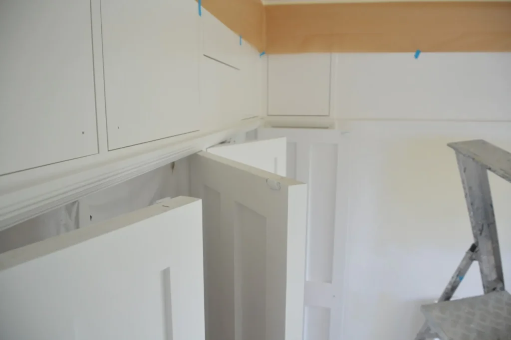 Cabinet doors sprayed in white with a ladder set up alongside