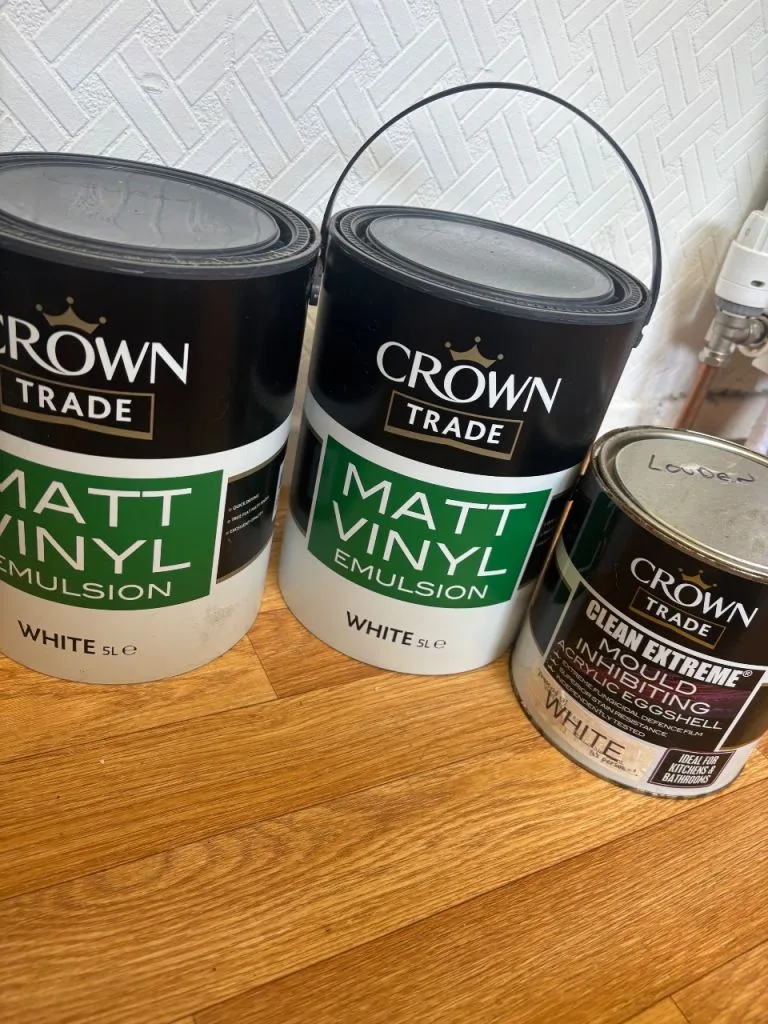 Tins of white emulsion paint on a wooden floor