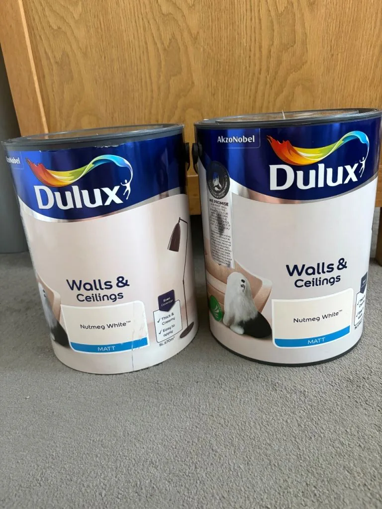 Two tins of white emulsion paint on a carpet