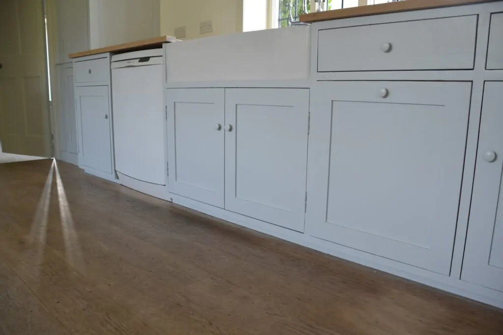 Kitchen units freshly sprayed in white with a wooden worktop