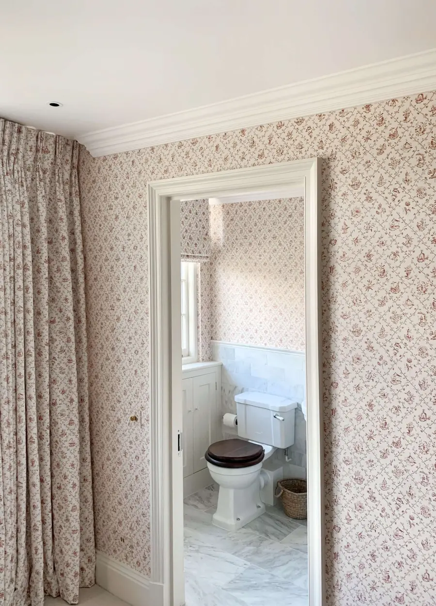Floral wallpaper pattern-matched to the curtains, with a wallpapered cloakroom beyond