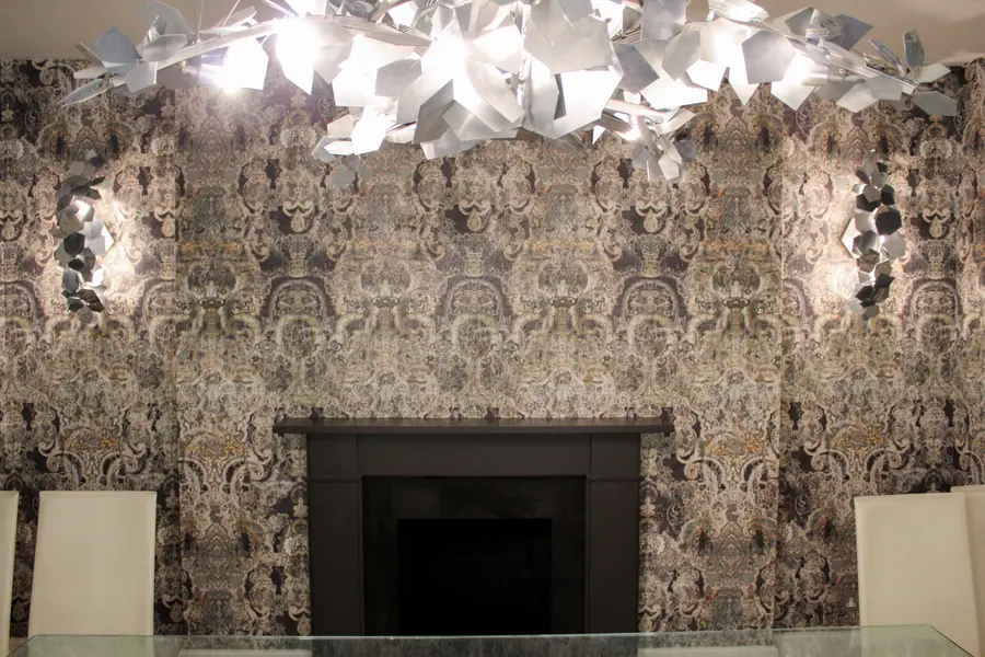 Dramatic damask wallpaper feature wall behind a fireplace