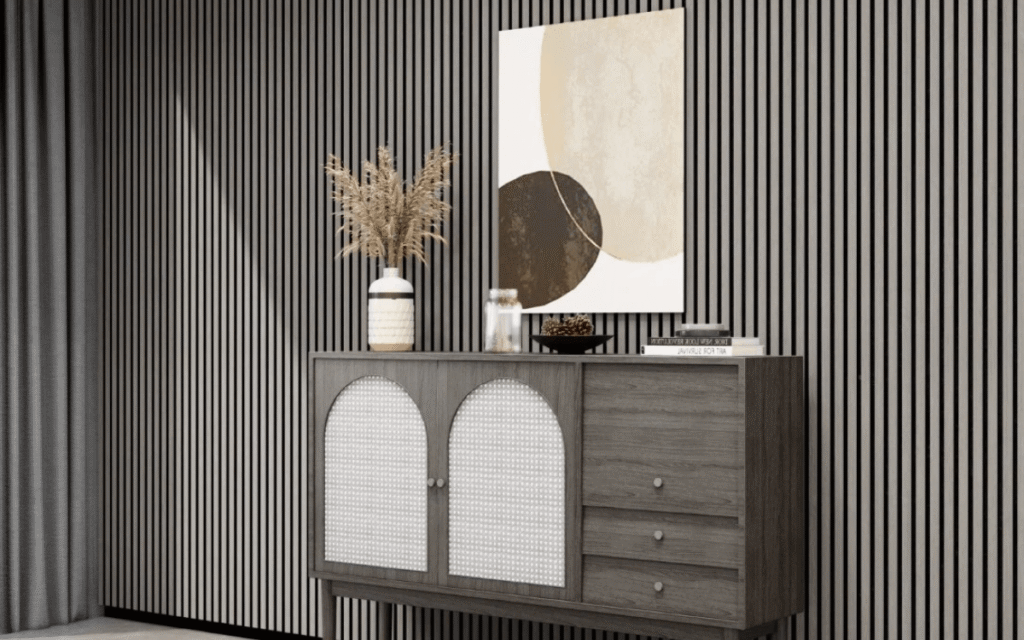 A modern sideboard with arched cabinet doors stands against a striped wall—a nod to Wallpaper Trends—topped with dried grass in a vase, a candle, and a bowl, beneath abstract artwork.