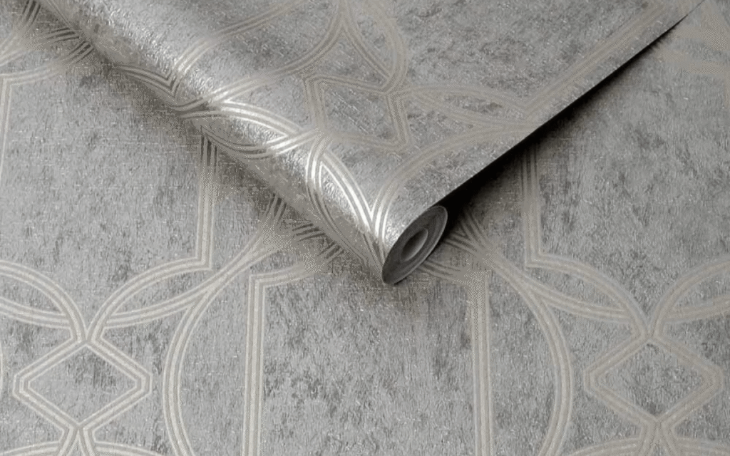 A rolled-up sheet of silver wallpaper with a geometric pattern, reflecting the latest wallpaper trends, is displayed on a flat surface.